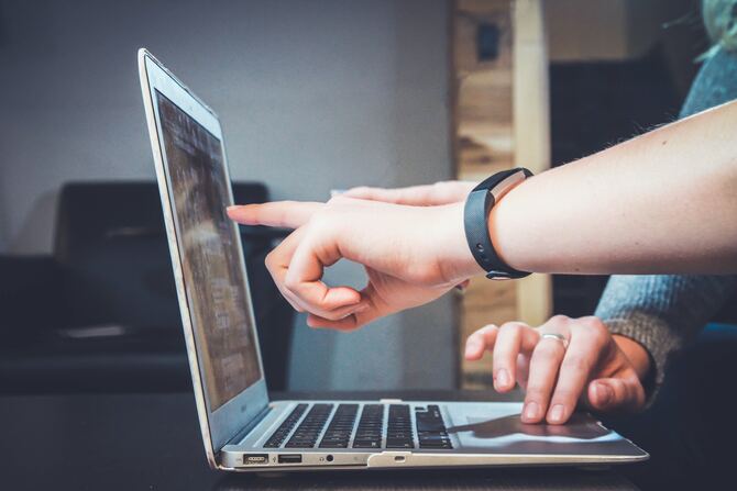 Hands pointing at the screen of a laptop computer