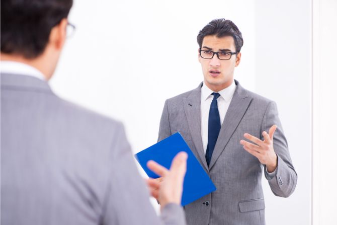 Man in suit practices delivering key messages in front of a mirror